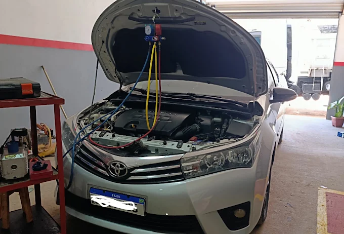Carro de passeio com capô aberto em manutenção de ar-condicionado